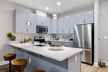 A modern kitchen with a white countertop and a stainless steel refrigerator.
